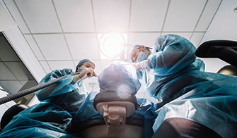 Periodontist and assistant performing a surgical procedure on a patient